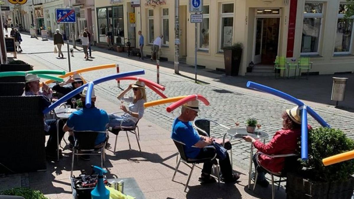 Distanțarea socială cu pălării și baghete de spumă colorate, pentru clienții unei cafenele