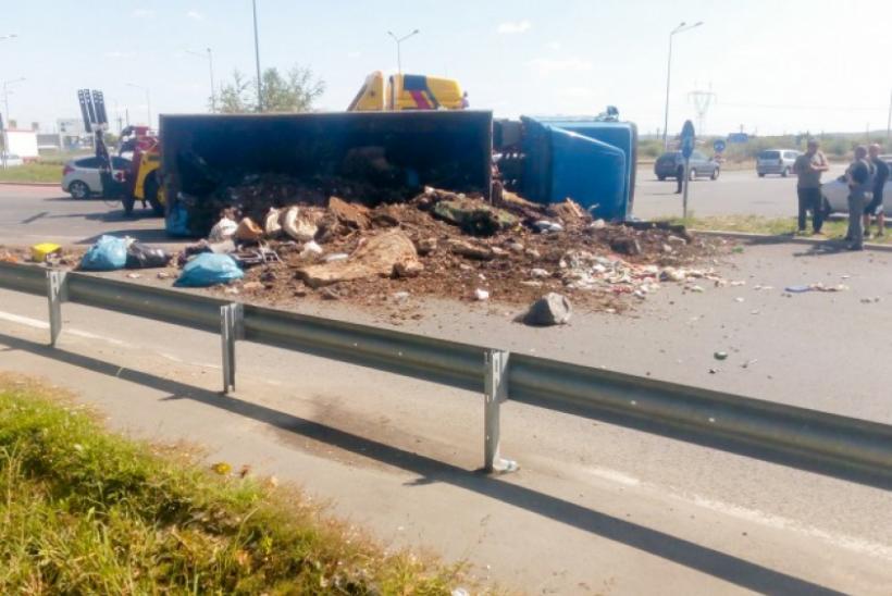 Imagine terifiantă pe o șosea din Oradea! Un camion plin de gunoi s-a răsturnat într-un sens giratoriu