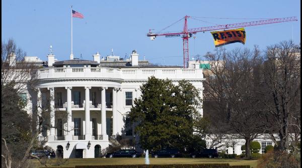 banner urias montat pe o macara din spatele casei albe