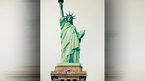 un grup de activisti au pus un urias banner pe statuia libertatii pe care scrie bun venit refugiati