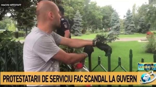 un barbat protesteaza legat de gardul guvernului pentru ca executivul sa nu adopte ordonanta pe amnistie si gratiere