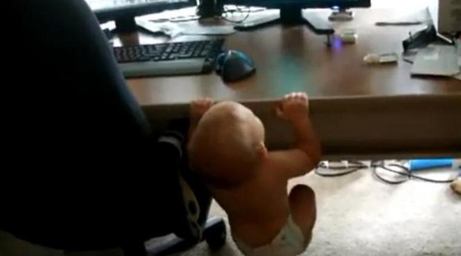 cu pampersii la purtator un bebelus de cateva luni face tractiuni pe marginea biroului video