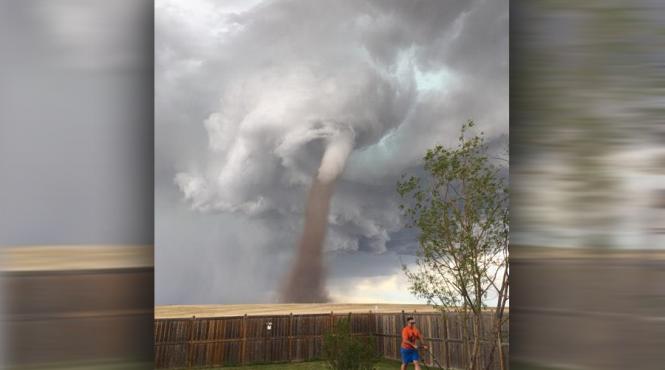 o fotografie in care un canadian tunde iarba in timp ce o tornada se afla in spatele lui face valva pe internet