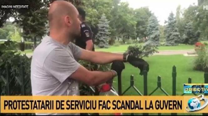 un barbat protesteaza legat de gardul guvernului pentru ca executivul sa nu adopte ordonanta pe amnistie si gratiere