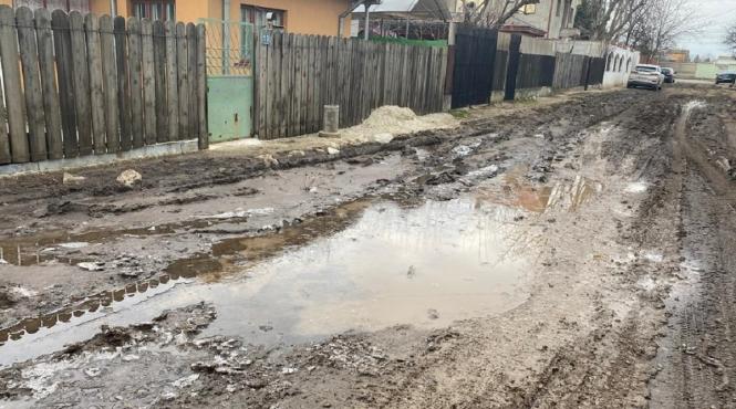 intrarea simleu in acte asfaltata pe teren scufundata in noroaie